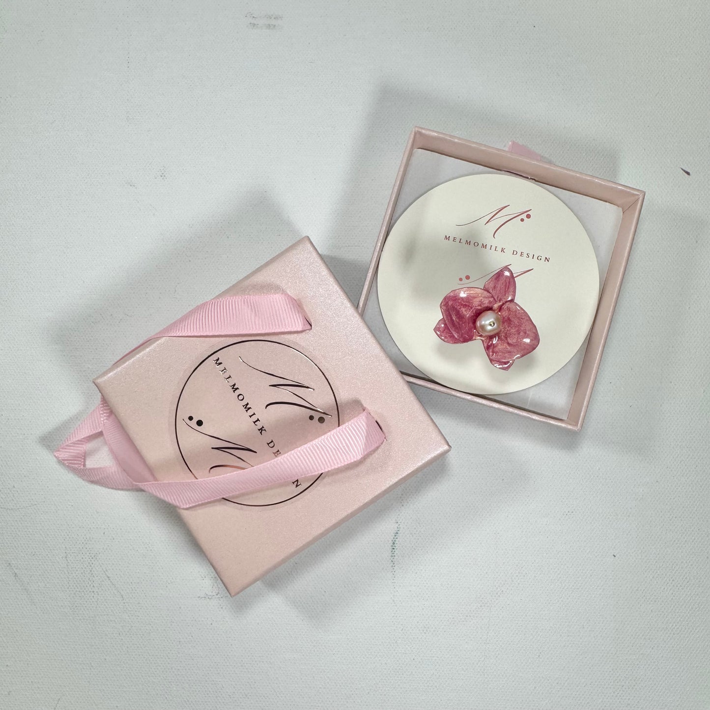 Handcrafted orchid flower ring in soft powder pink, made from upcycled materials with a velvet-like finish.