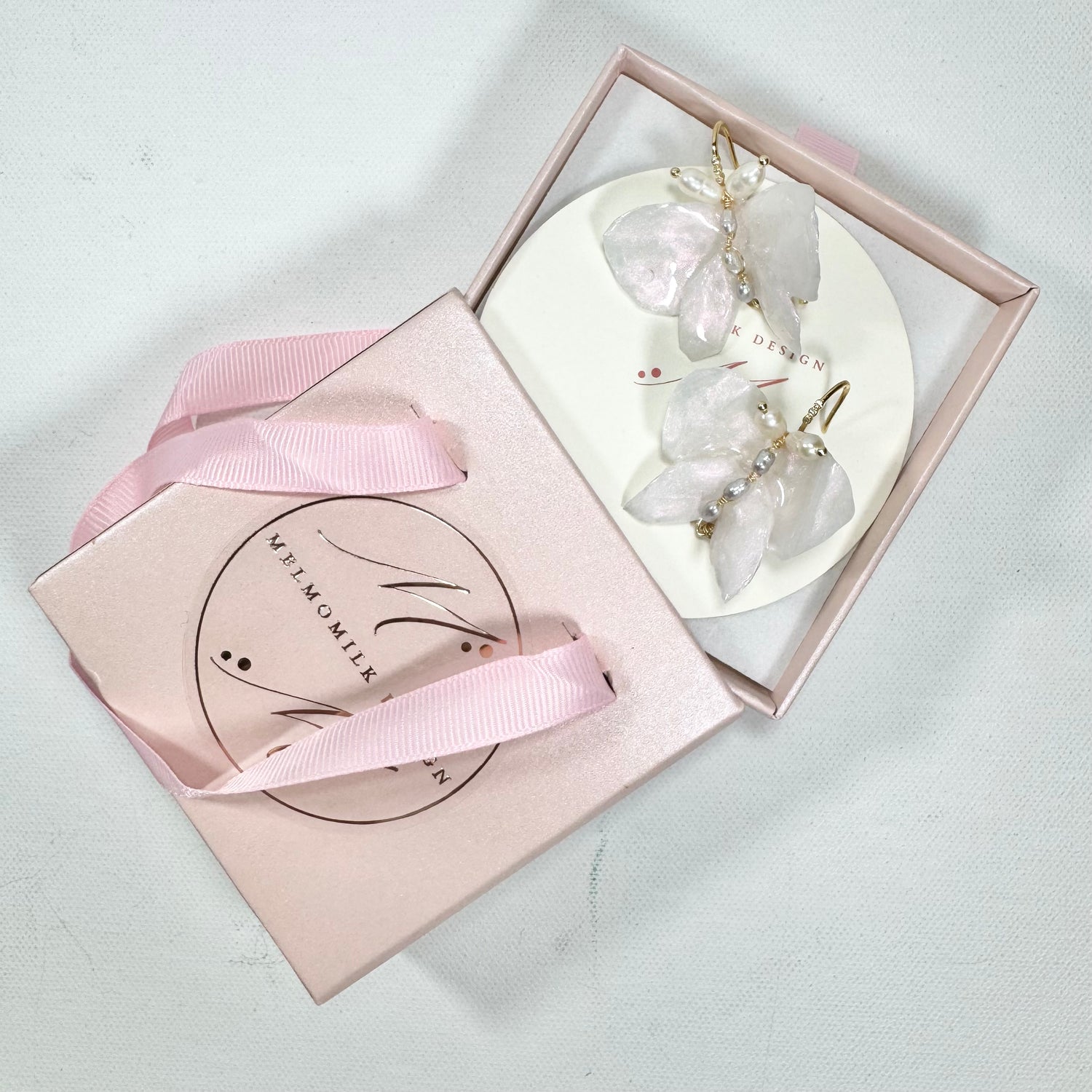 Handcrafted butterfly-shaped earrings in pearl white, made from upcycled materials and finished in a luminous White Silk tone.