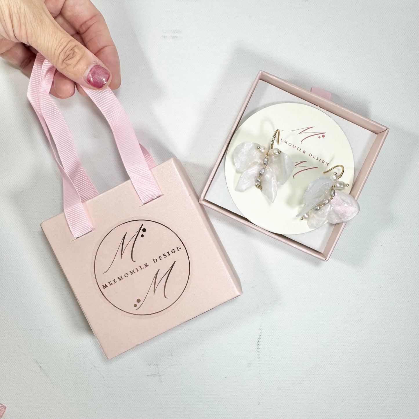 Handcrafted butterfly-shaped earrings in pearl white, made from upcycled materials and finished in a luminous White Silk tone.
